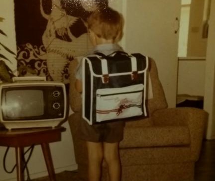 The obligatory "first day of school" shot of a tiny child with an ENORMOUS backpack. In the background: the entirety of the 1980s, apparently.